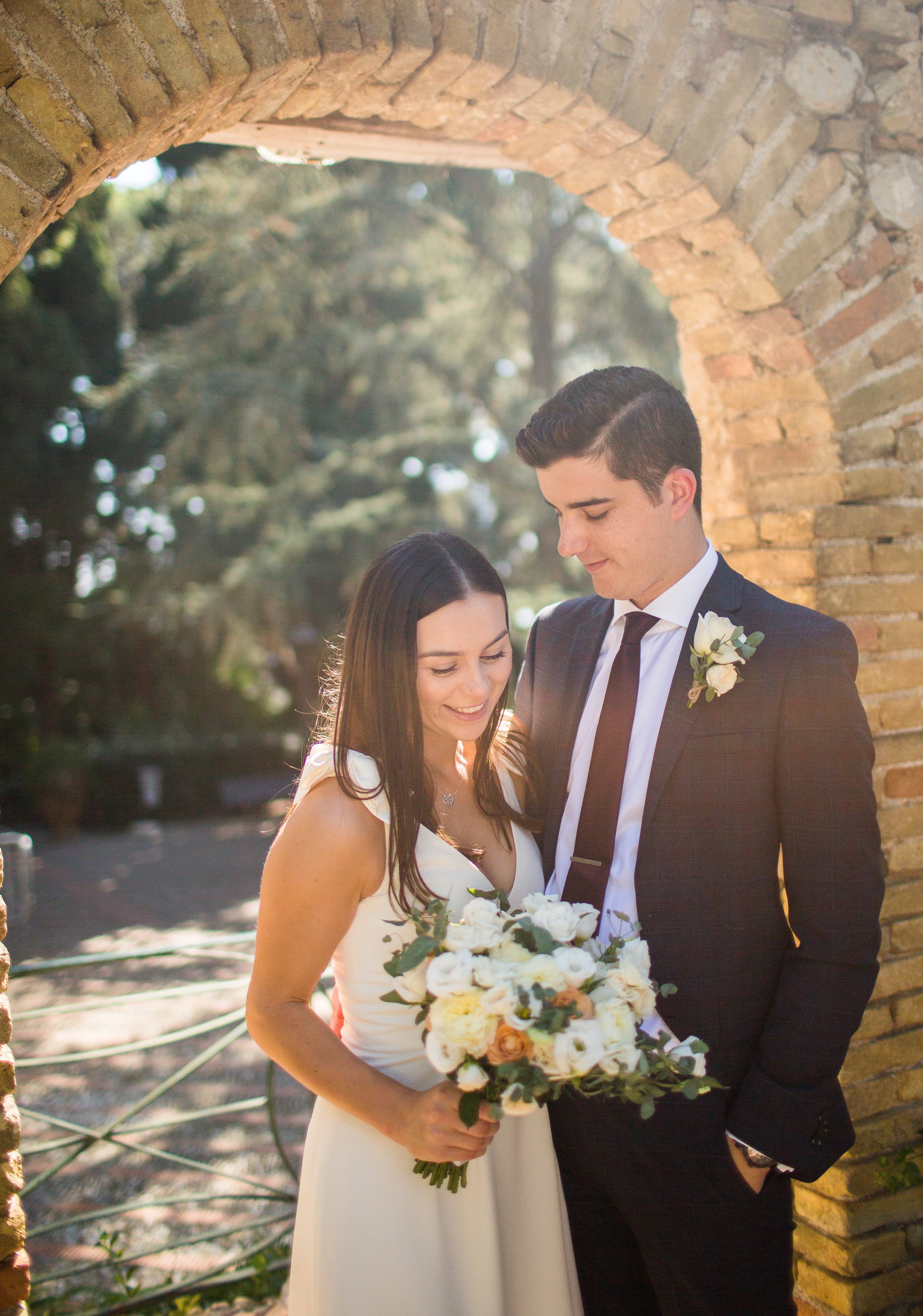 Couple framed by a rustic brick arch at their Sicilian wedding