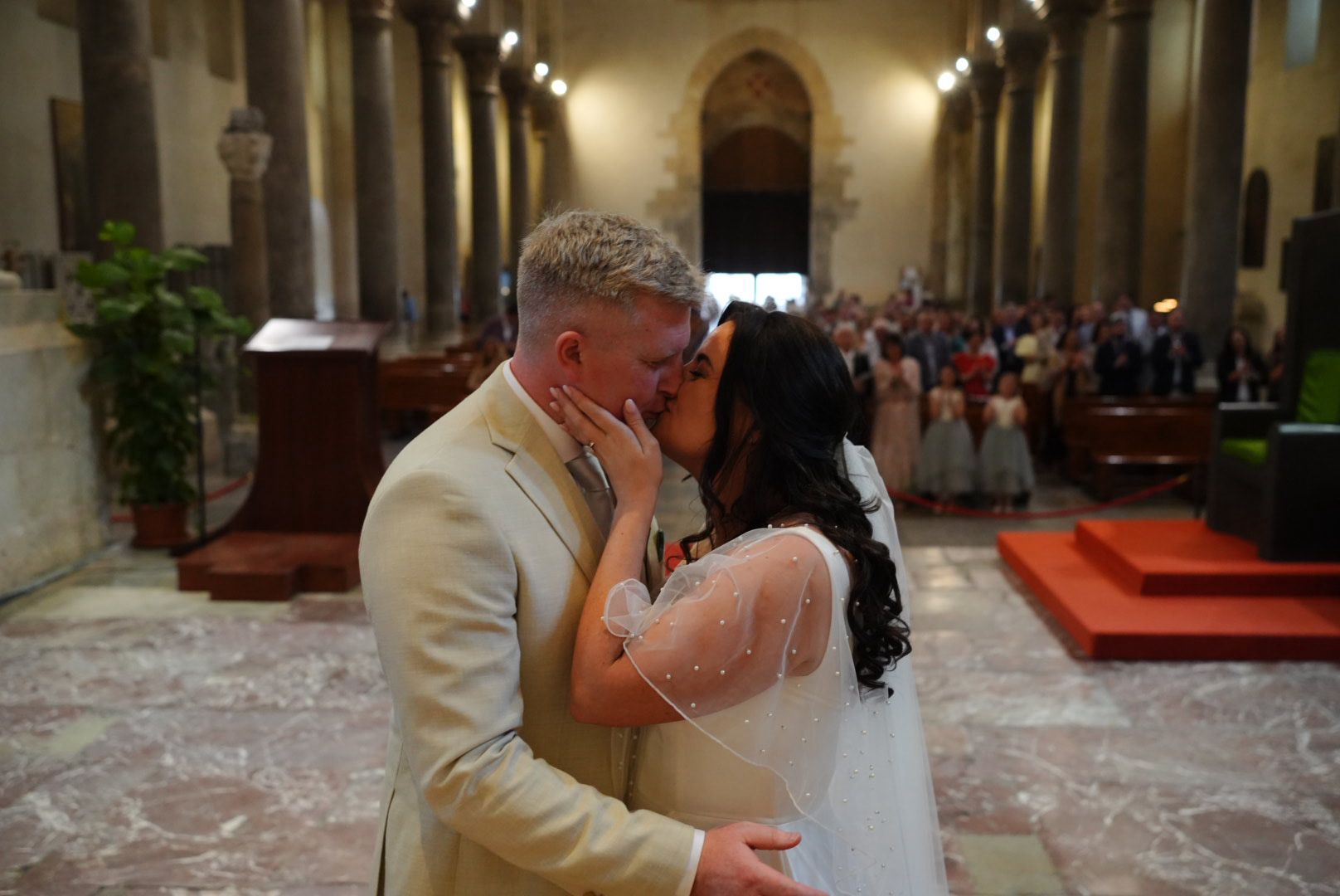 Bride and groom kissing on the steps of a Sicilian cathedral