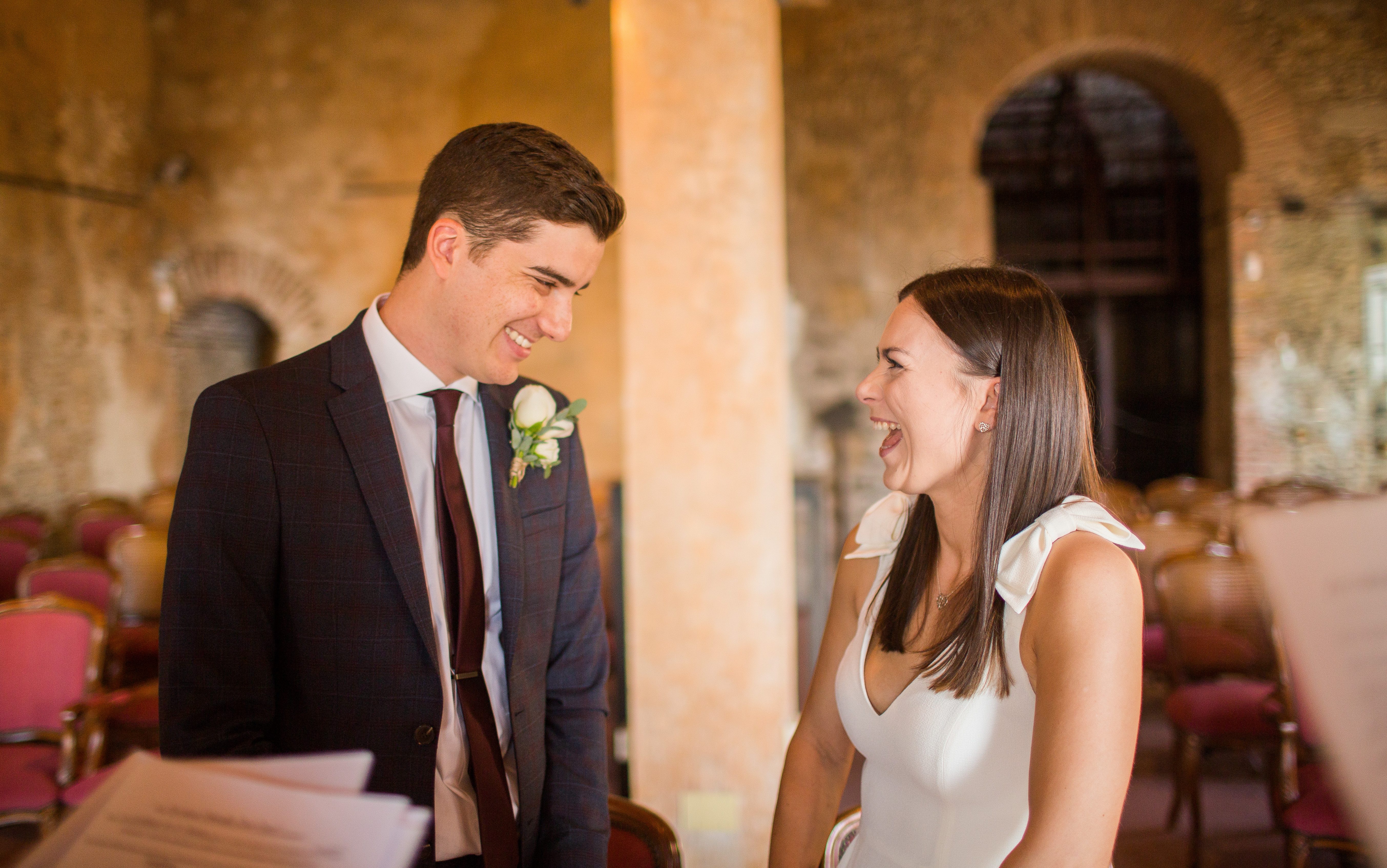 Newlyweds laughing together indoors on their wedding day