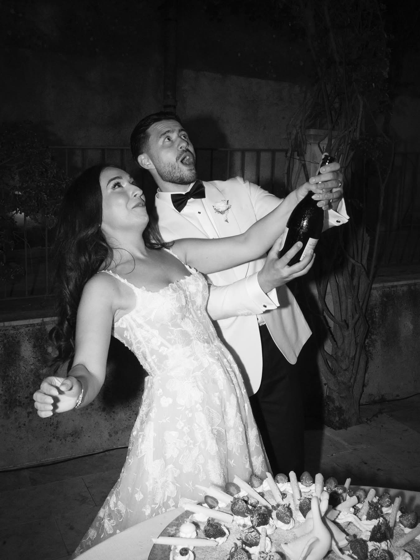Una foto in bianco e nero dello champagne stappato sopra la torta nuziale in stile millefoglie