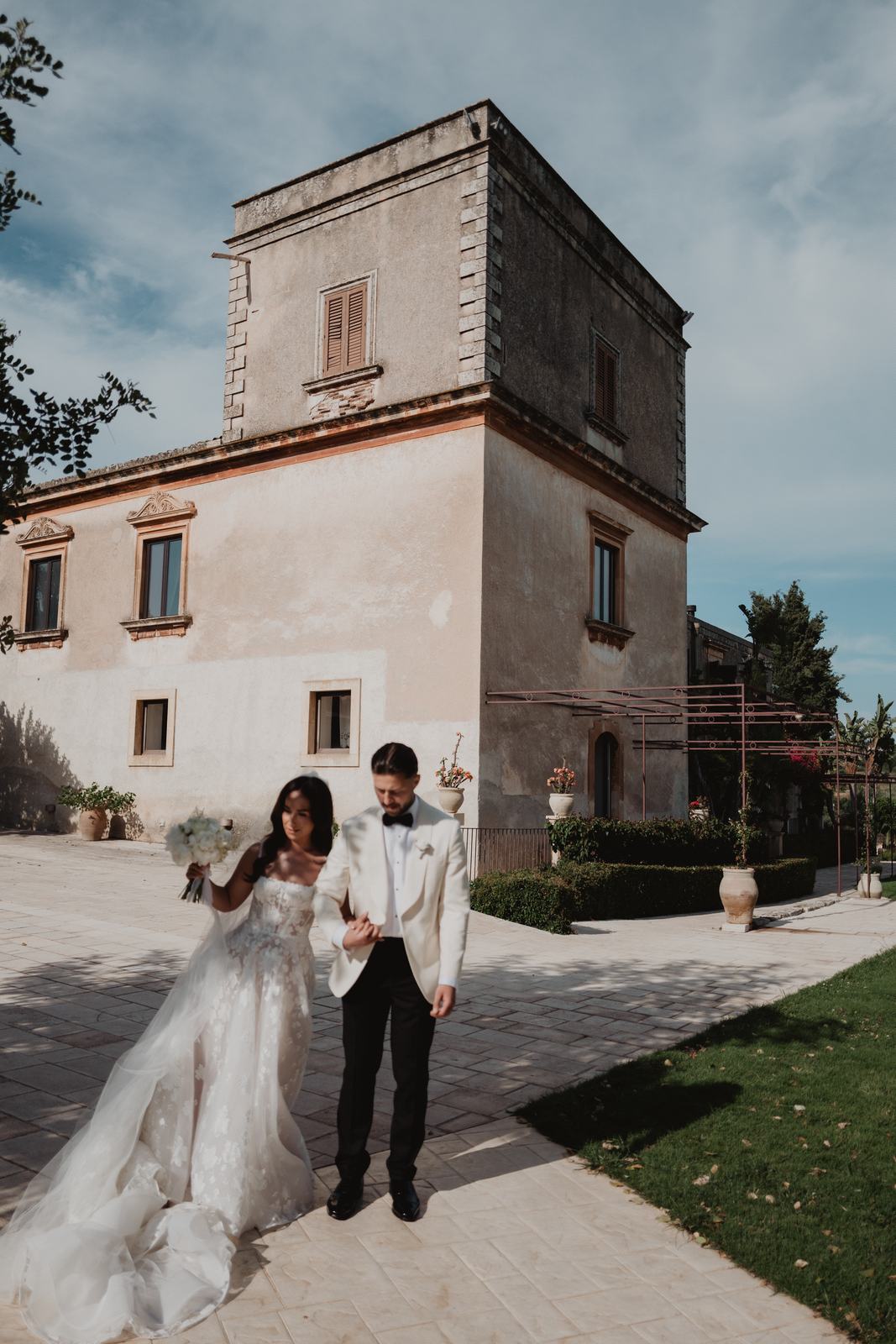 Gli sposi davanti alla villa in pietra con la torre del Borgo del Carato, nella Sicilia sud-orientale