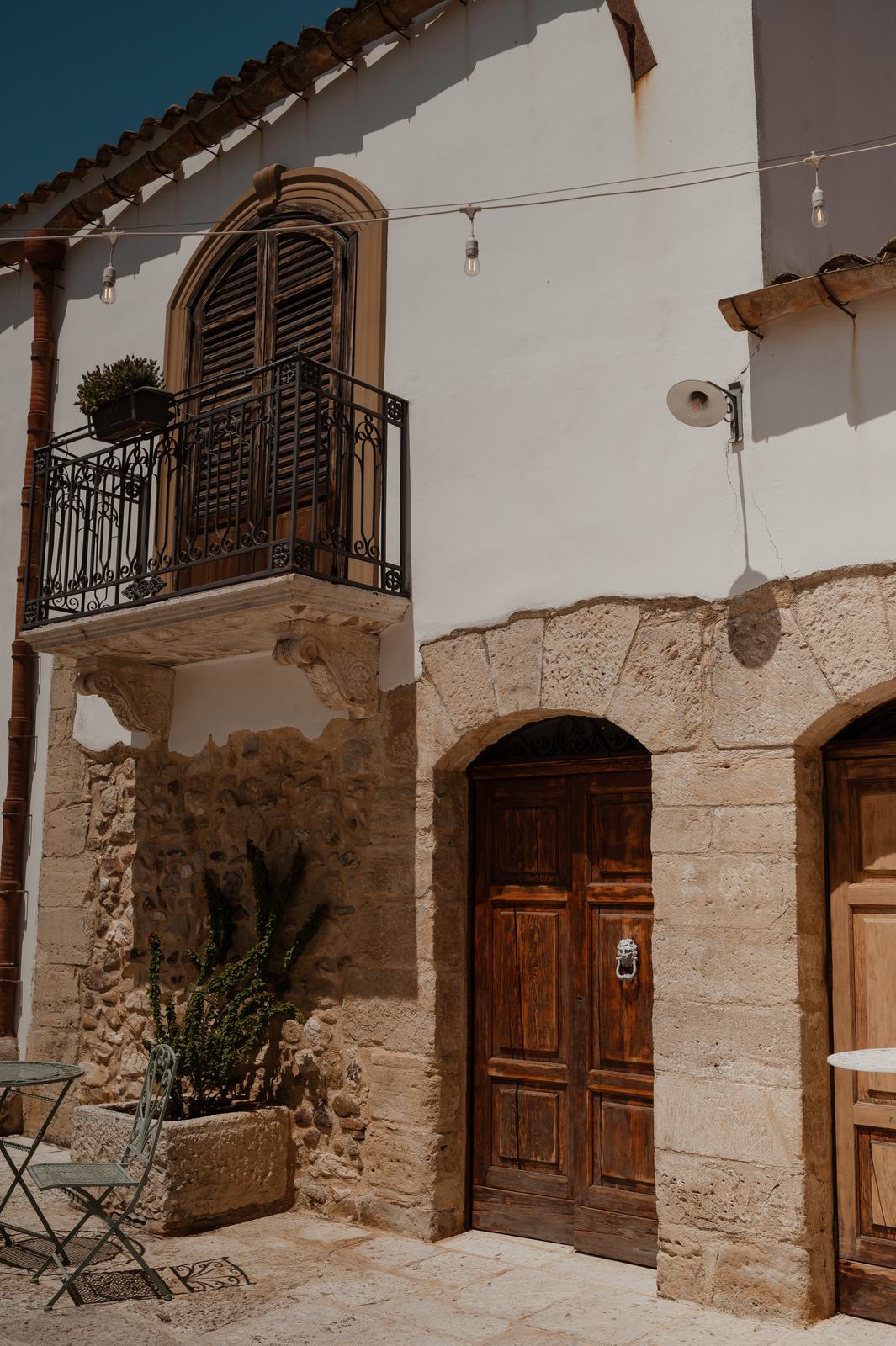 Il cortile storico del Casale degli Aranci, con archi in pietra, porte in legno e un balcone in ferro battuto