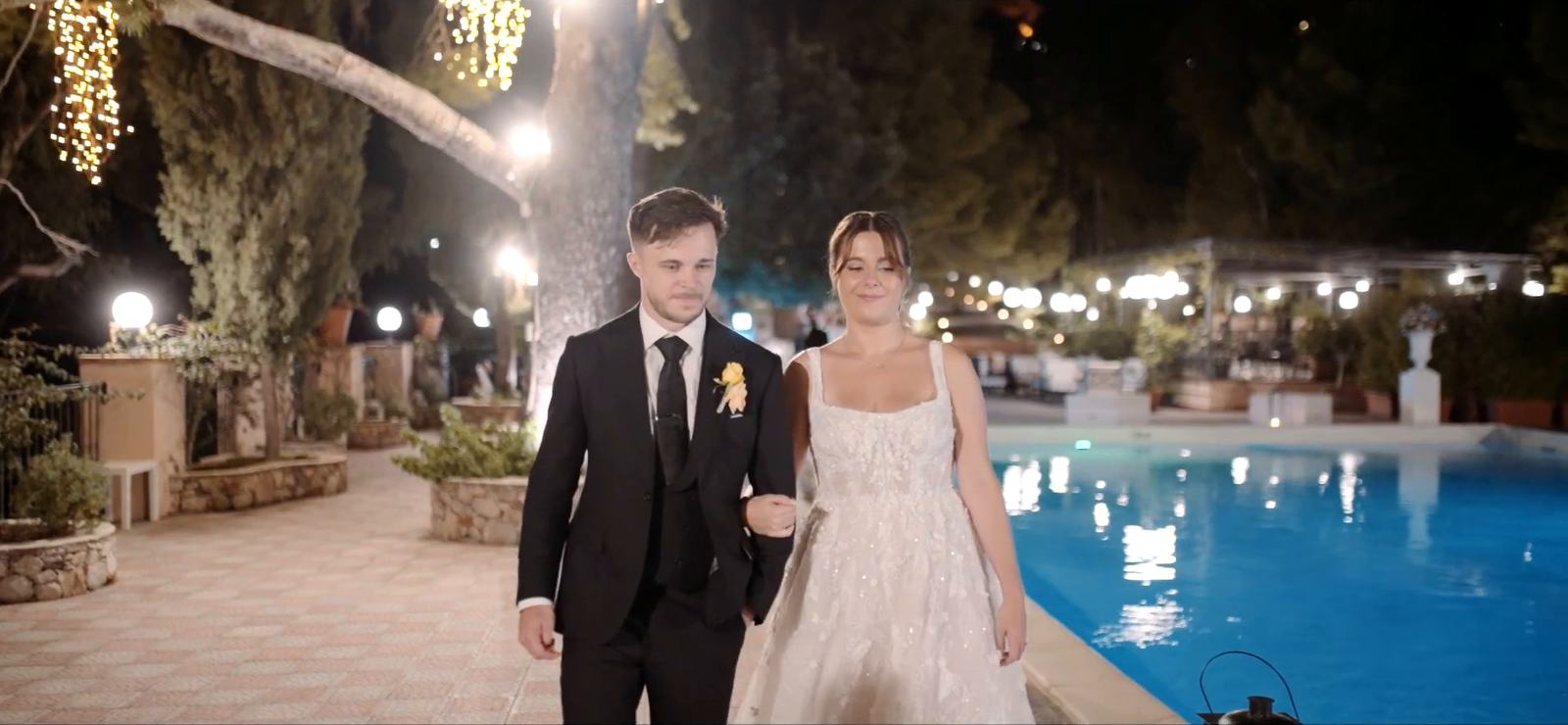 Gli sposi passeggiano accanto alla piscina dell’Excelsior Palace di Taormina la sera del matrimonio