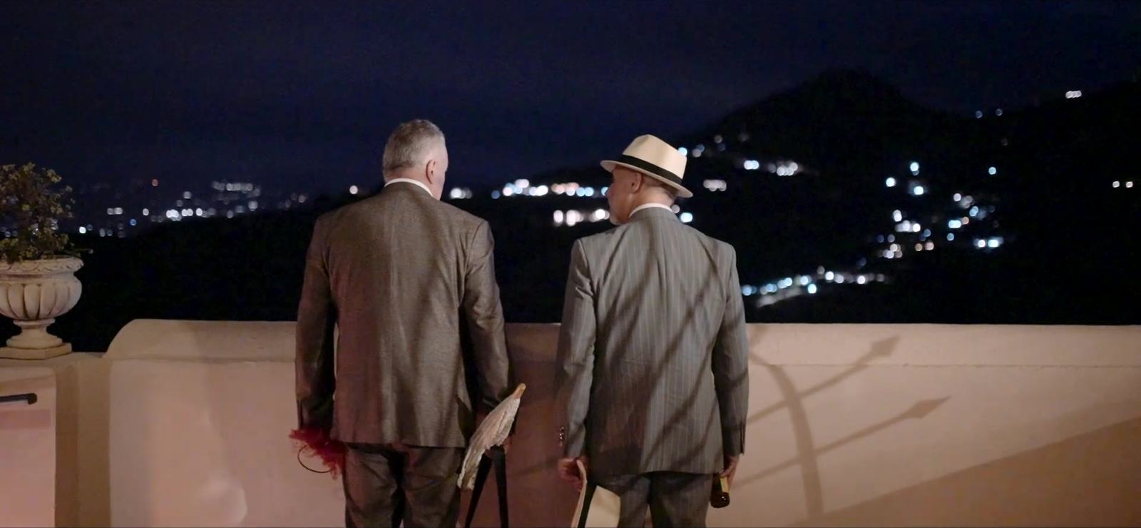 Ospiti del matrimonio su una terrazza dell’Excelsior Palace affacciata sulle luci della costa di Taormina di notte