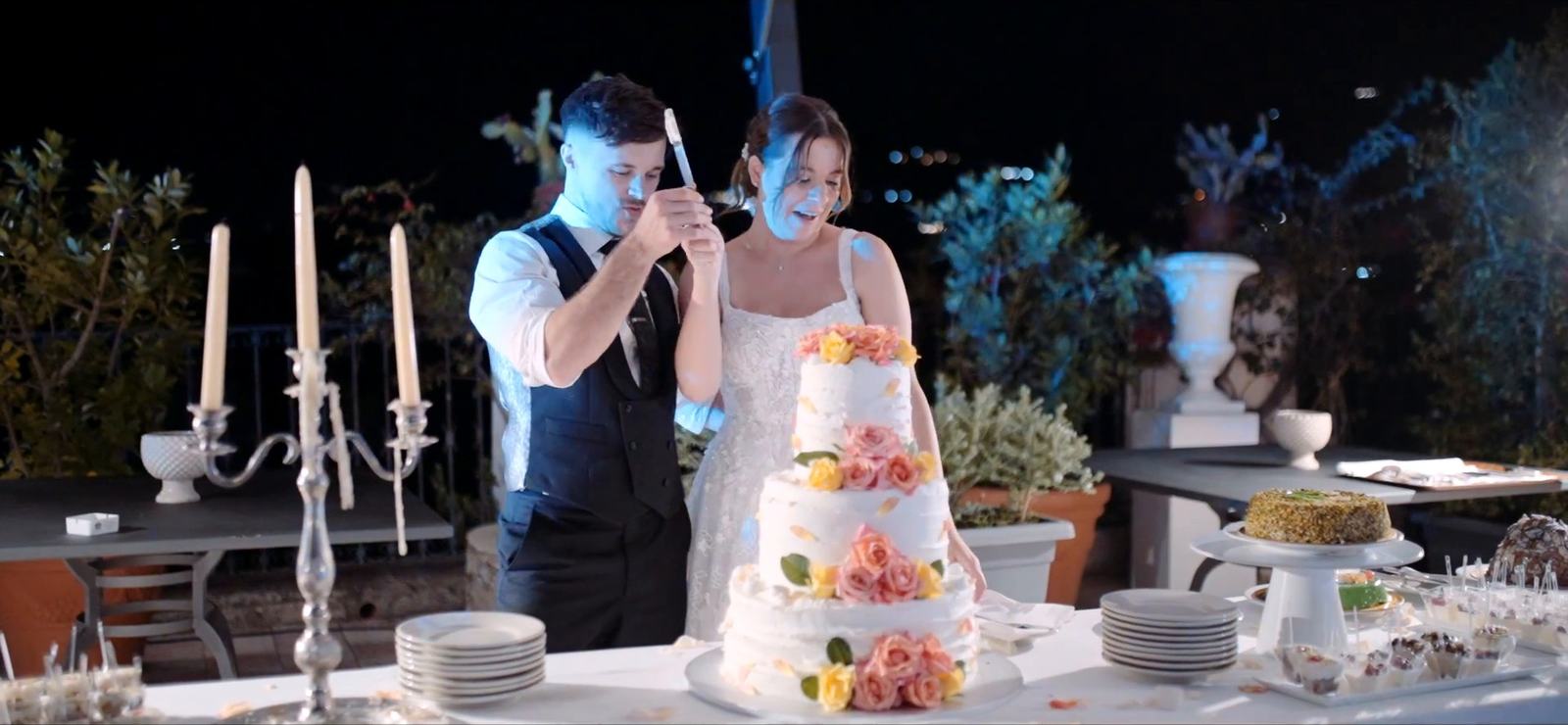Gli sposi tagliano la torta nuziale nel parco dell’Excelsior Palace in una sera di settembre